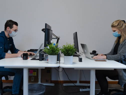 deux personnes travaillent en face à face derrière avec un masque pour lutter contre le covid 19